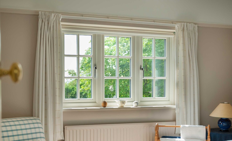 White multi-pane heritage style window in a bright room with greenery visible outside.